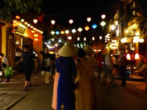 Des touristes asiatiques en tenues traditionnelles se baladent au milieu des lampions de Hoi An