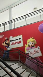 Mur coloré à l’aéroport du Japon avec Mario disant “Bienvenue au Japon”, symbole du début du voyage et du besoin d’internet.