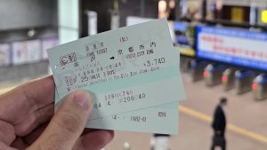 Main tenant plusieurs billets JR Pass dans la gare de Kanazawa, prêts pour un voyage à travers le Japon.