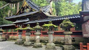 Temple de Nikkō caché dans la forêt, avec des sculptures recouvertes de mousse au premier plan.