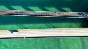 Vue drone dans les Florida Keys montrant deux ponts parallèles au-dessus d’une eau vert émeraude.